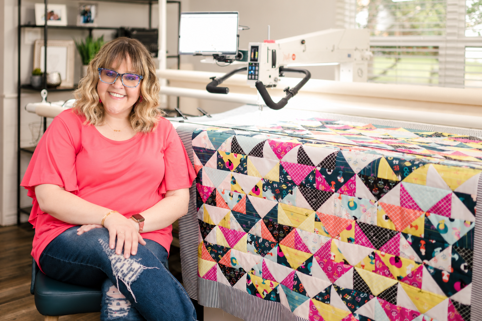 Christen beside her longarm with a colorful quilt on the frame