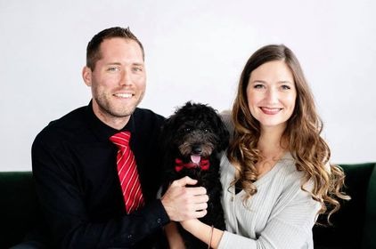 couple holding their black mini golden-doodle