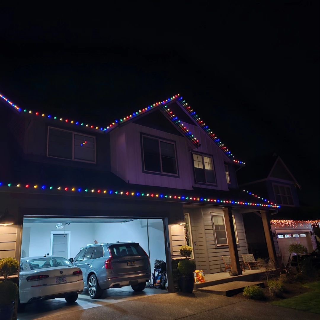 Professional Christmas light installation across a wide roofline and trees