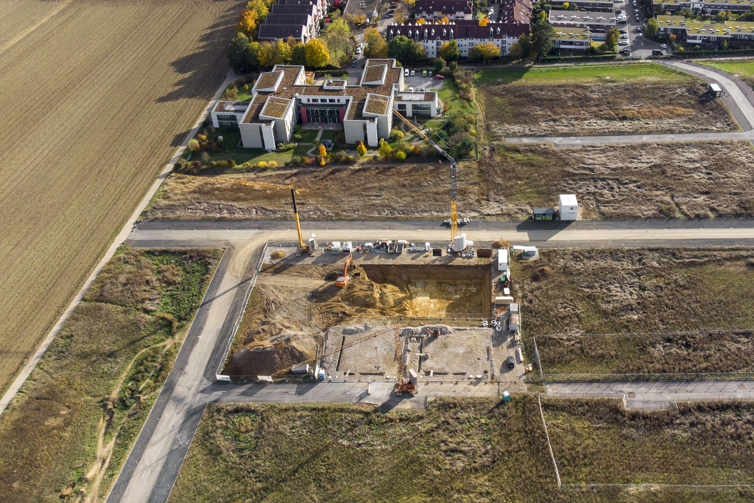 Aerial view of a land development site with roads, excavated ground and nearby buildings