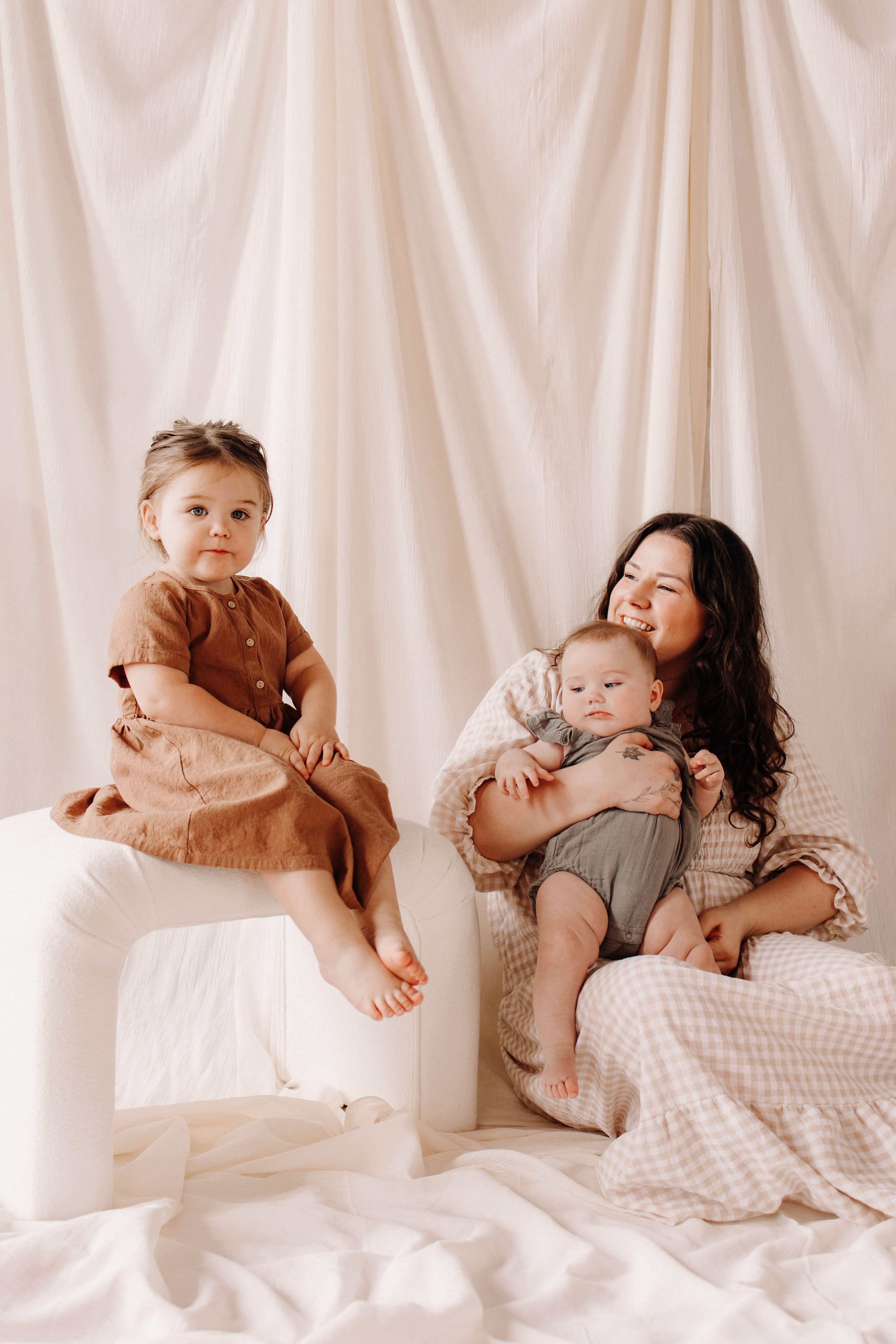 Kelsie with her two children in a soft cream studio