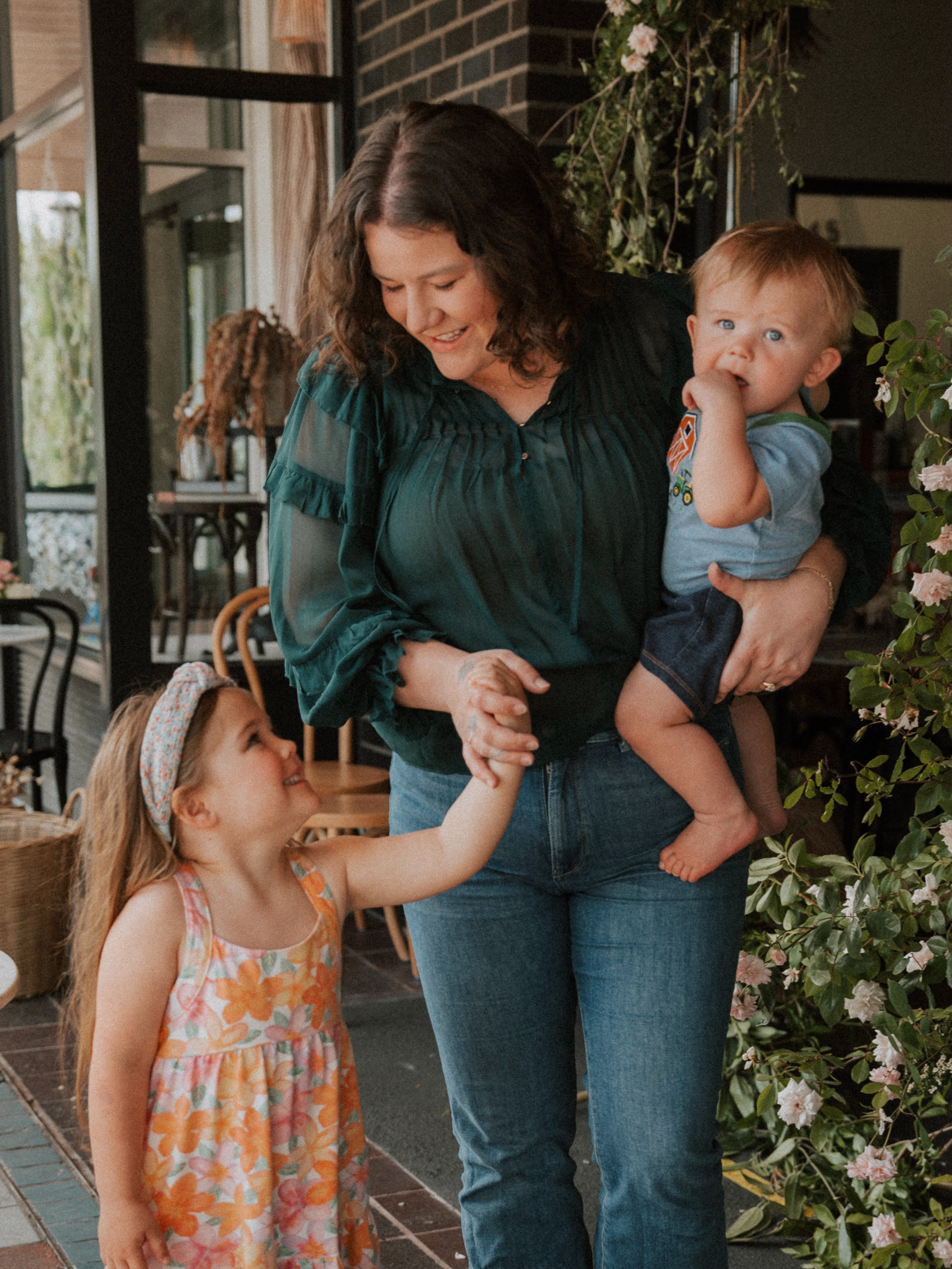 Kelsie holding her son while her daughter takes her hand outside a storefront