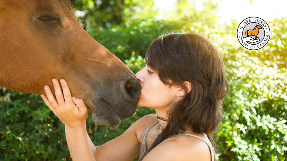 Woman gently kissing a horse in equine therapy programs session Woman gently kissing a horse in equine therapy programs session