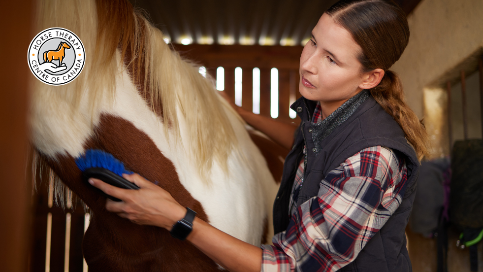 Woman grooming a horse as part of hands-on therapy session Woman grooming a horse as part of hands-on therapy session