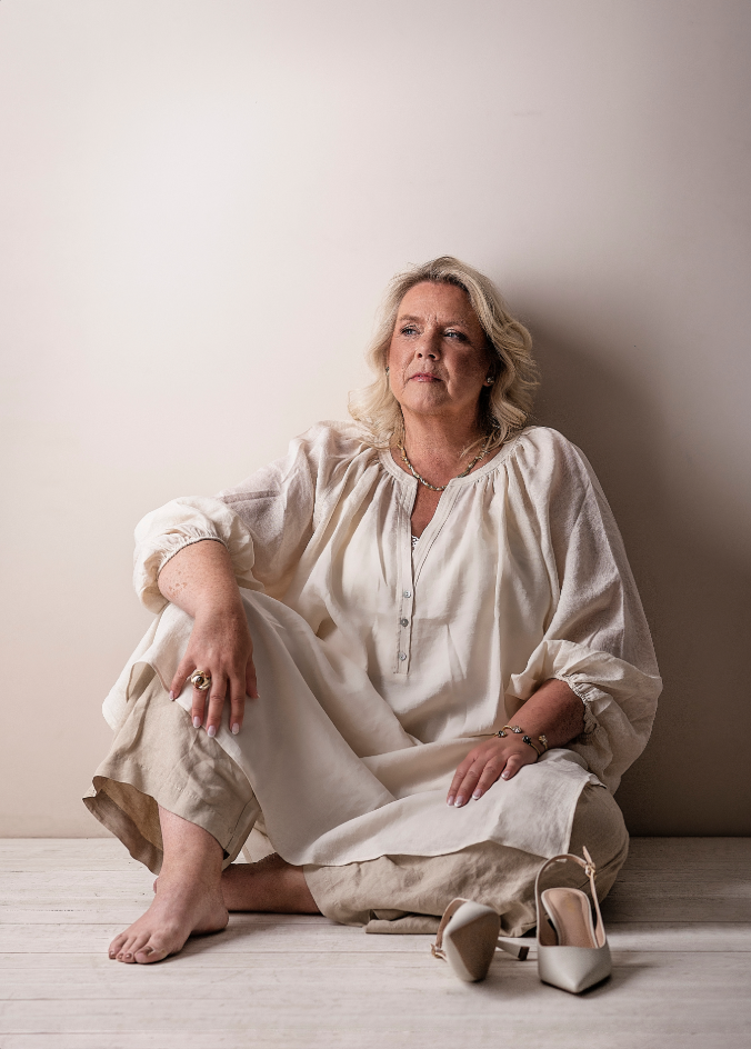 Camilla seated barefoot in linen. The whole woman behind the mission.