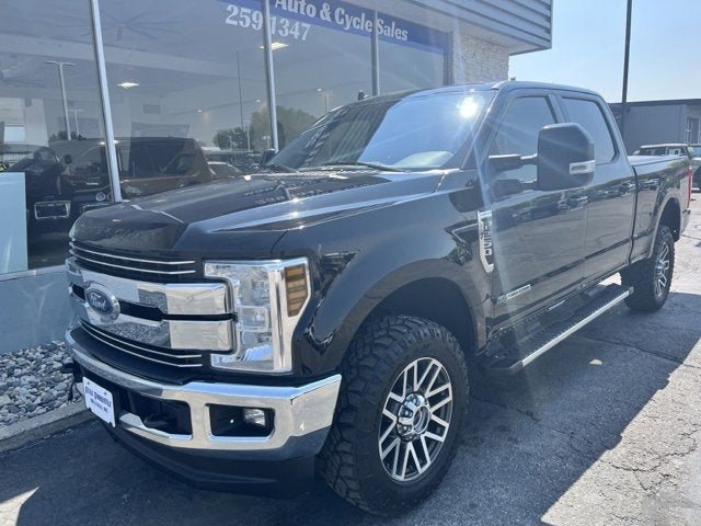 A black Ford F-250 parked in front of the Full Throttle Auto & Cycle Sales showroom