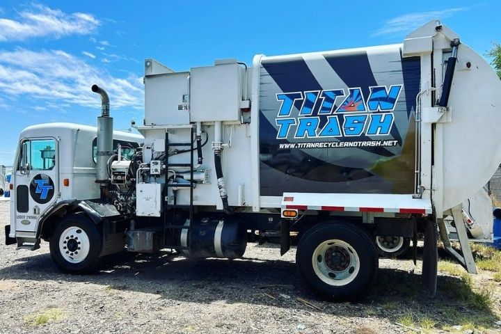 A trash truck servicing a residential bin as part of the local tucson trash schedule.