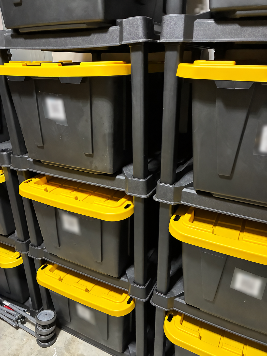 Close view of my yellow-lid storage bins in their rack, with QR codes and identifying labels heavily blurred.