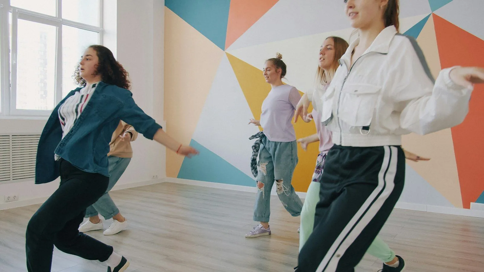 Teens dancing hip hop in front of a colourful geometric mural