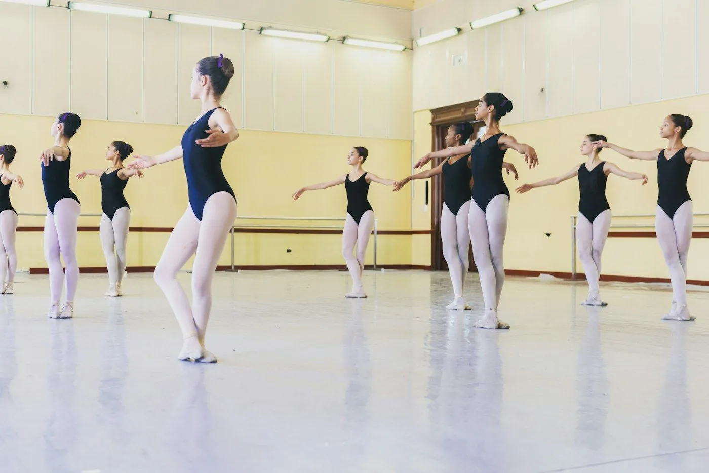 Young ballet students in leotards practising in a bright studio