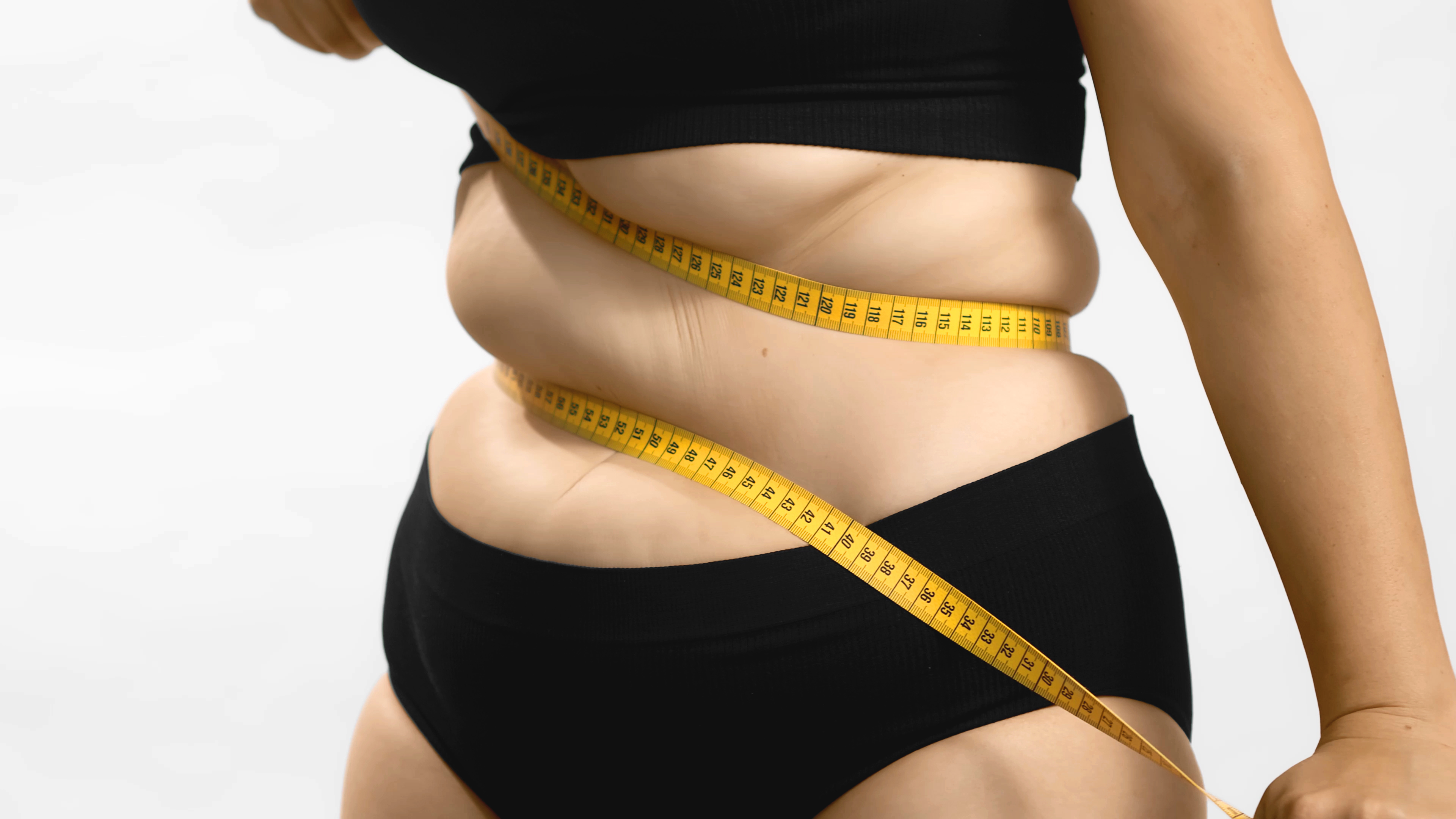 Woman measuring waist struggling with weight loss cycle without diet or exercise changes