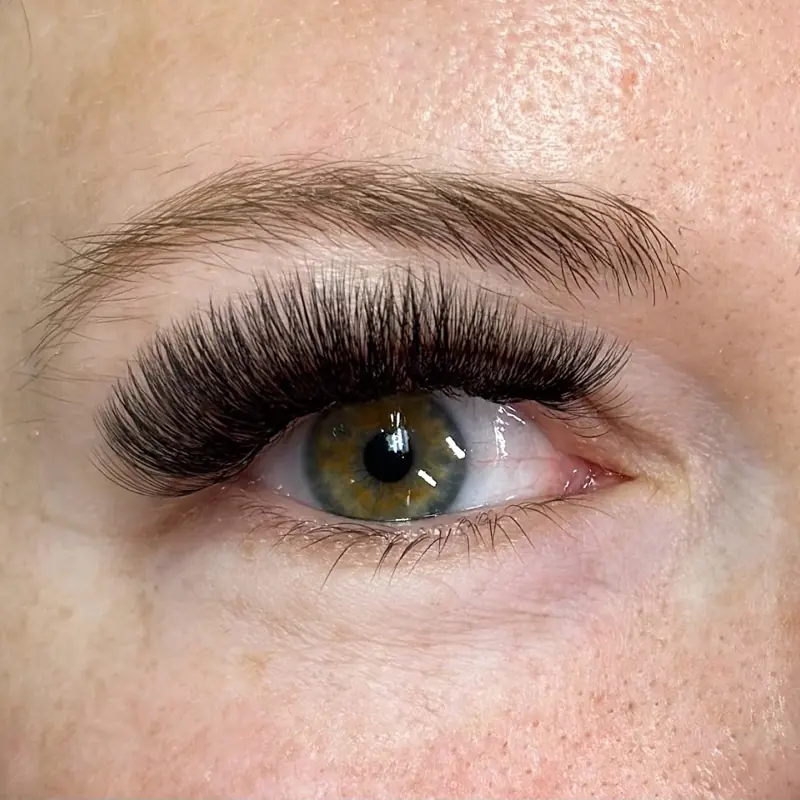 Close-up of a full set of eyelash extensions on a client with green eyes