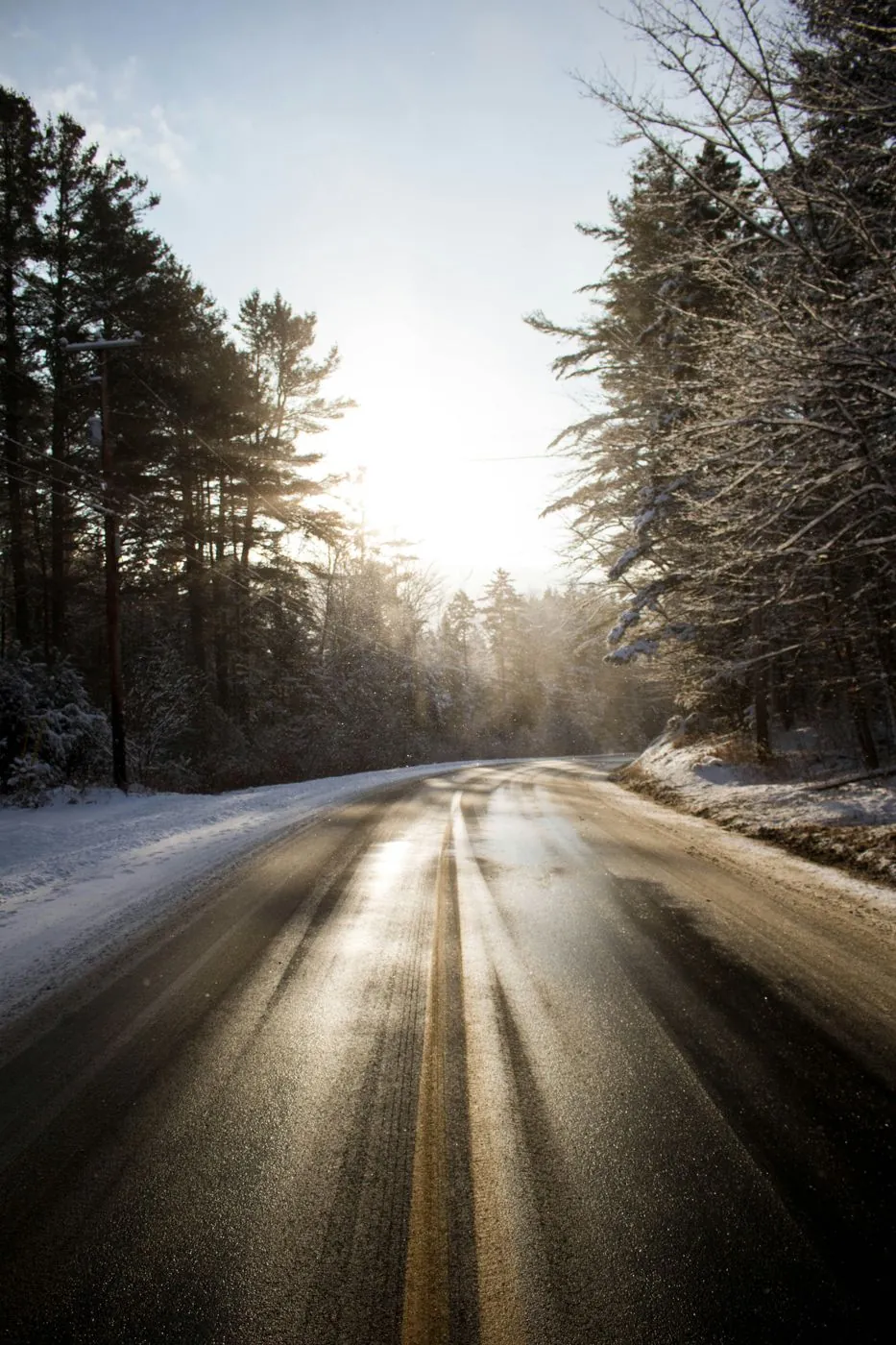 A Vermont mountain road through snowy pines in low winter sun