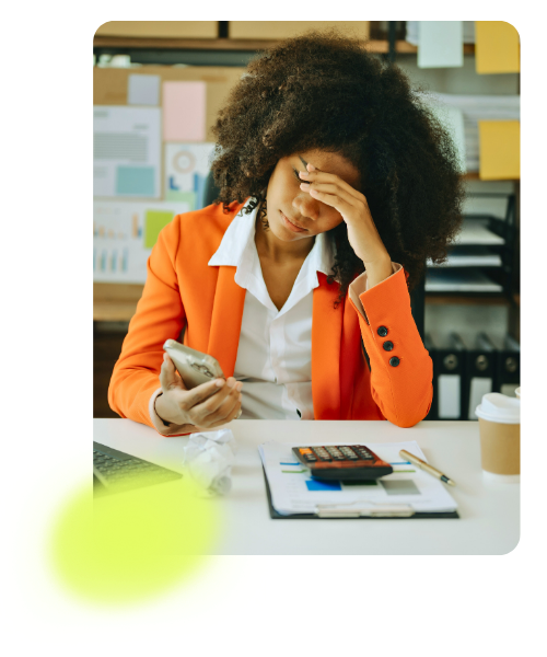 Stressed woman working at her desk looking at her phone