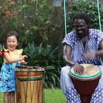 African Beat drummer helping a young child play a djembe