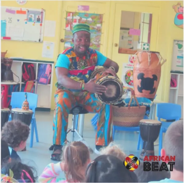 Master Drummer Tuza teaching kindy children to play the drums in a classroom