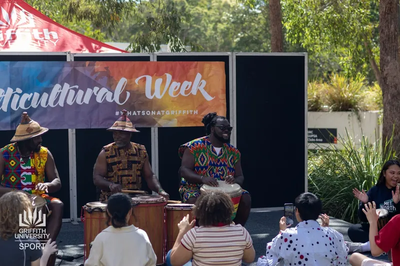 African Beat drummers performing on a Multicultural Week stage to a seated audience