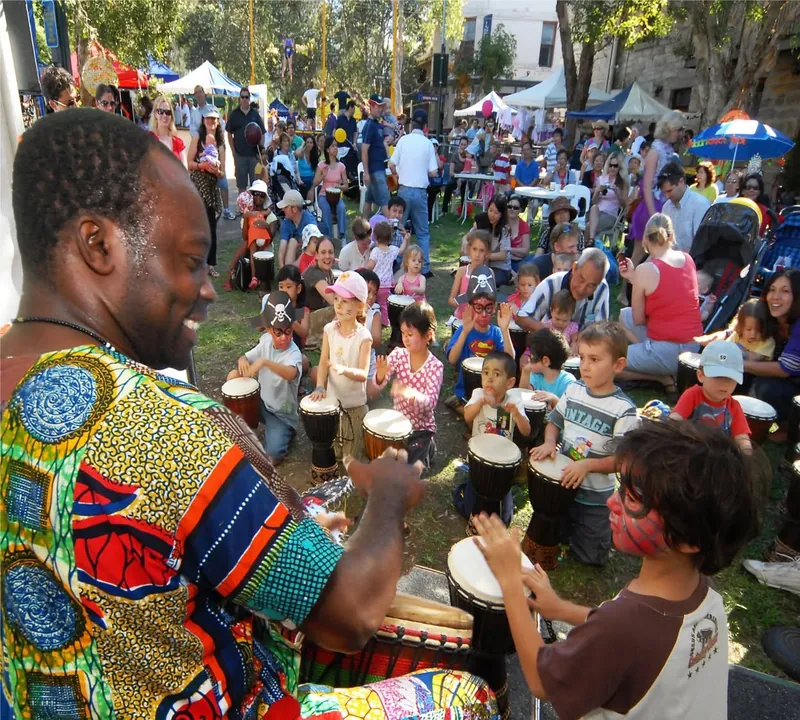 African Beat drummer leading an interactive drumming workshop for a large outdoor crowd