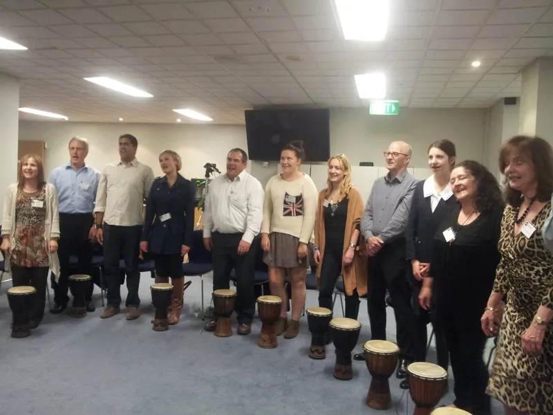 Corporate team standing in an office with djembe drums in front of them, ready for an African Beat workshop