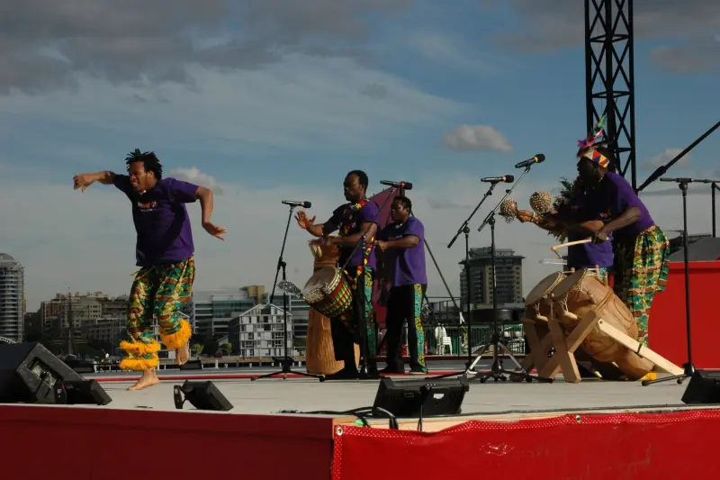 African Beat outdoor stage performers drumming and dancing at dusk on an Australian festival stage
