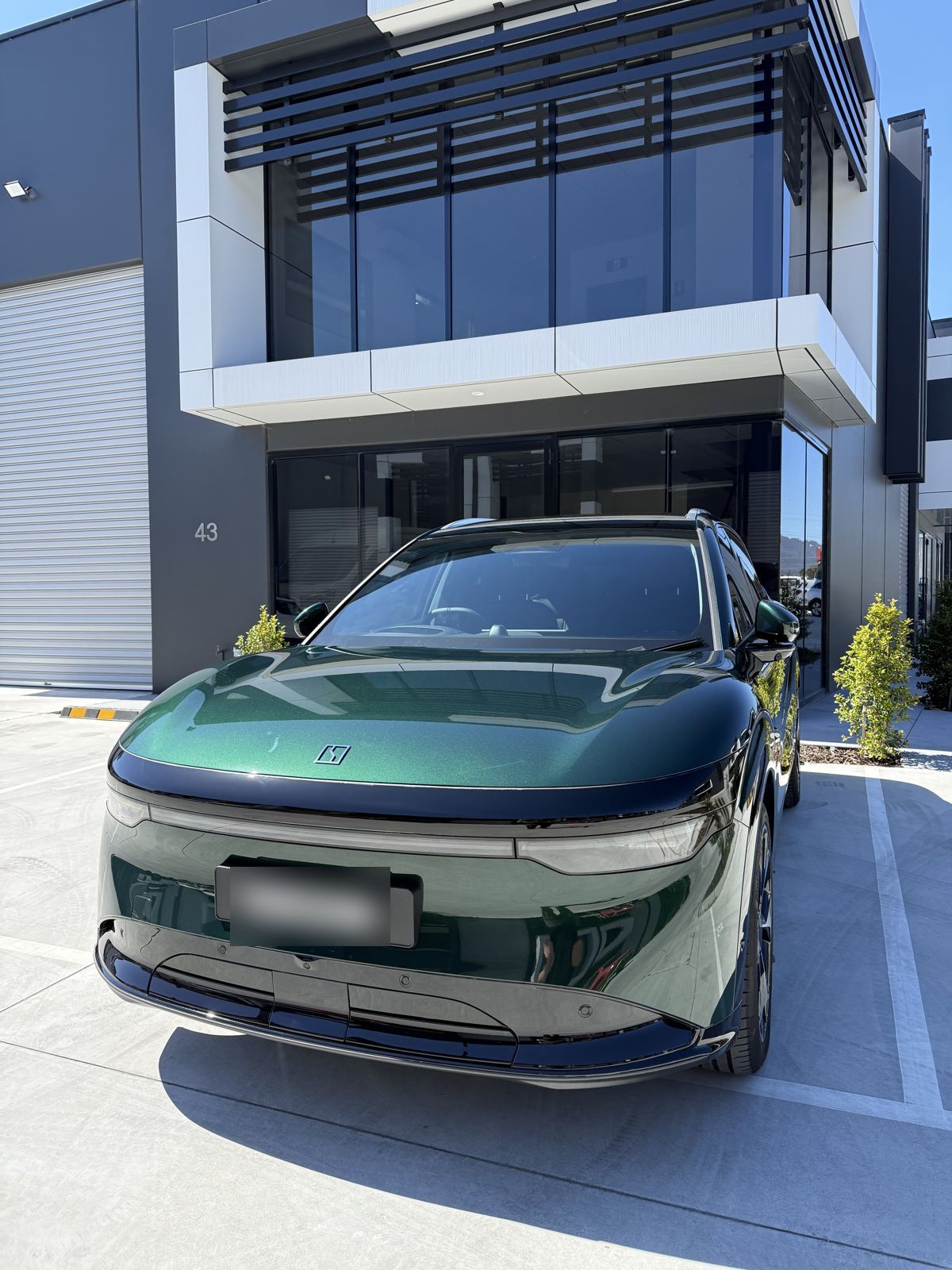 Finished green SUV with gloss paint protection film parked outside the studio in sunlight