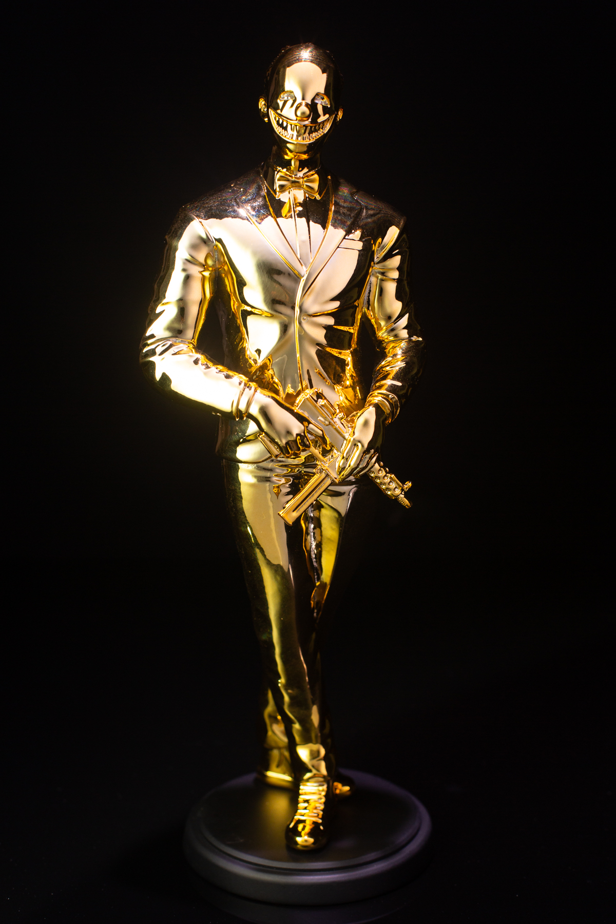 The Cuzzie: a gold figure in a tuxedo and bow tie wearing a grinning horror mask