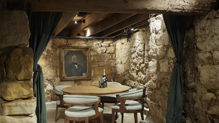 Round table and upholstered chairs in a stone-walled room with timber beams