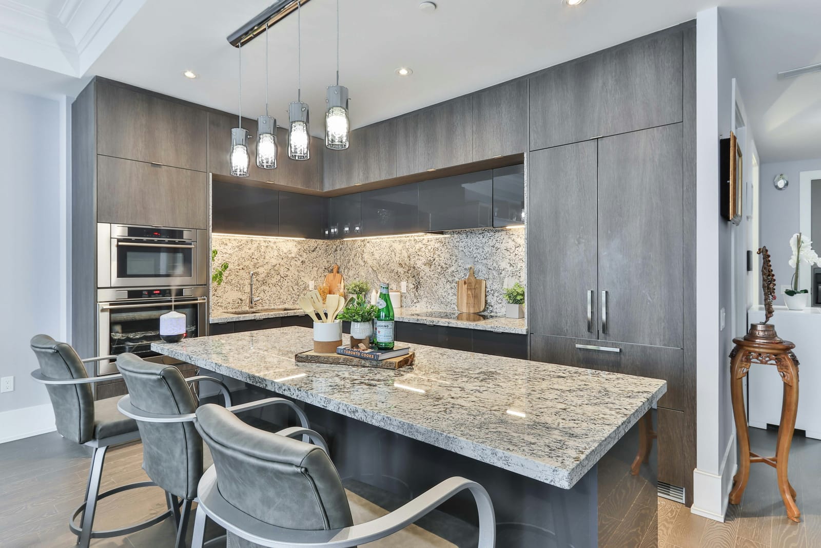 A modern condo kitchen with a stone island and bar stools
