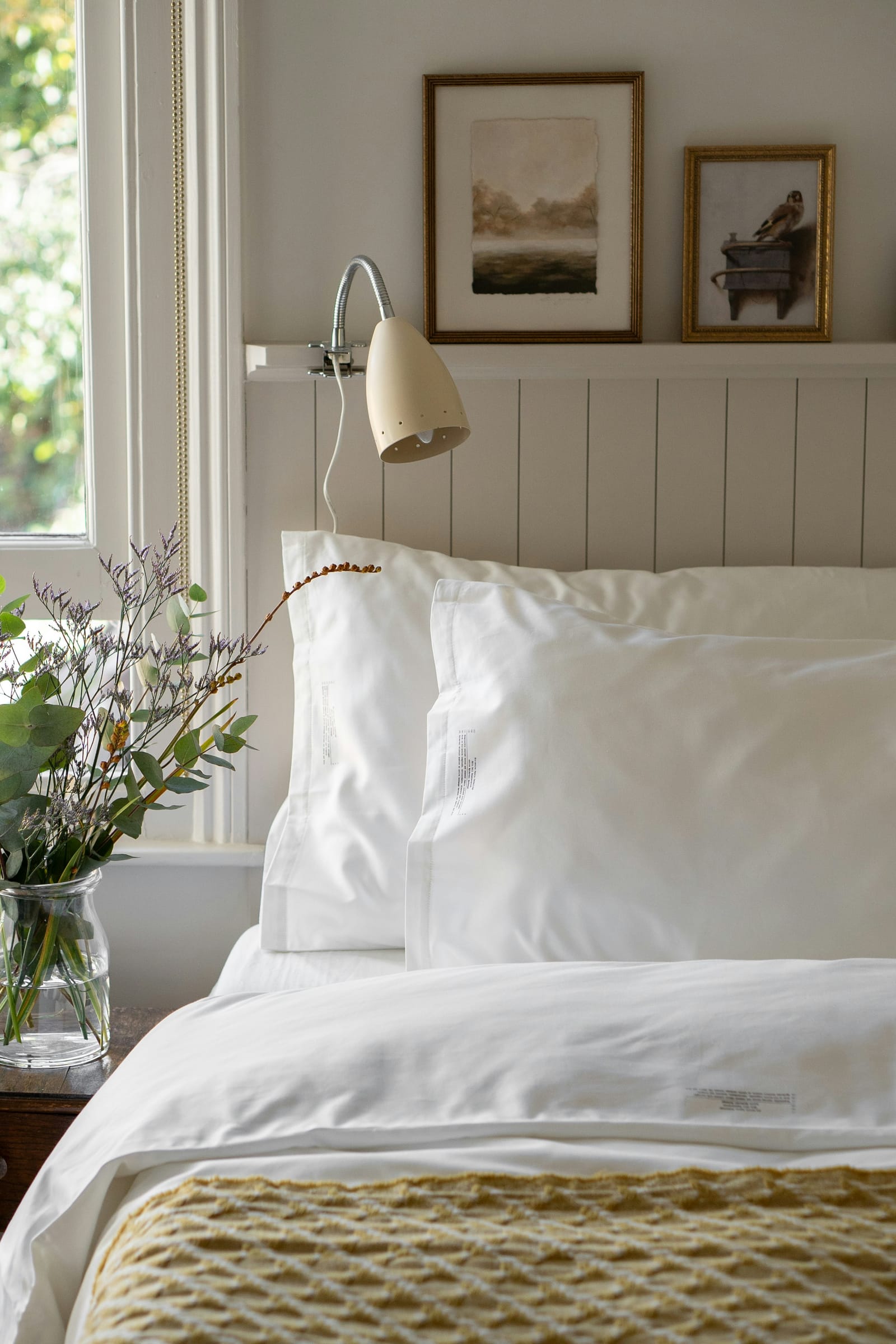 A neatly made bed with crisp white linen and a soft grey throw