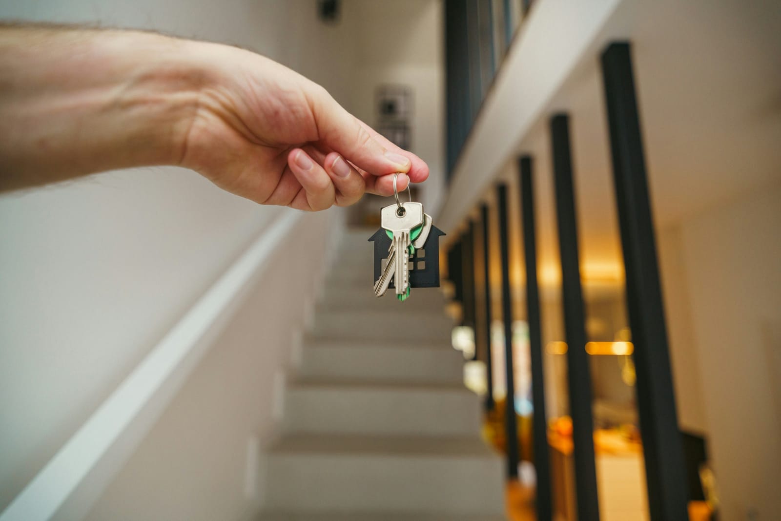 A hand holding a set of keys in a bright stairwell