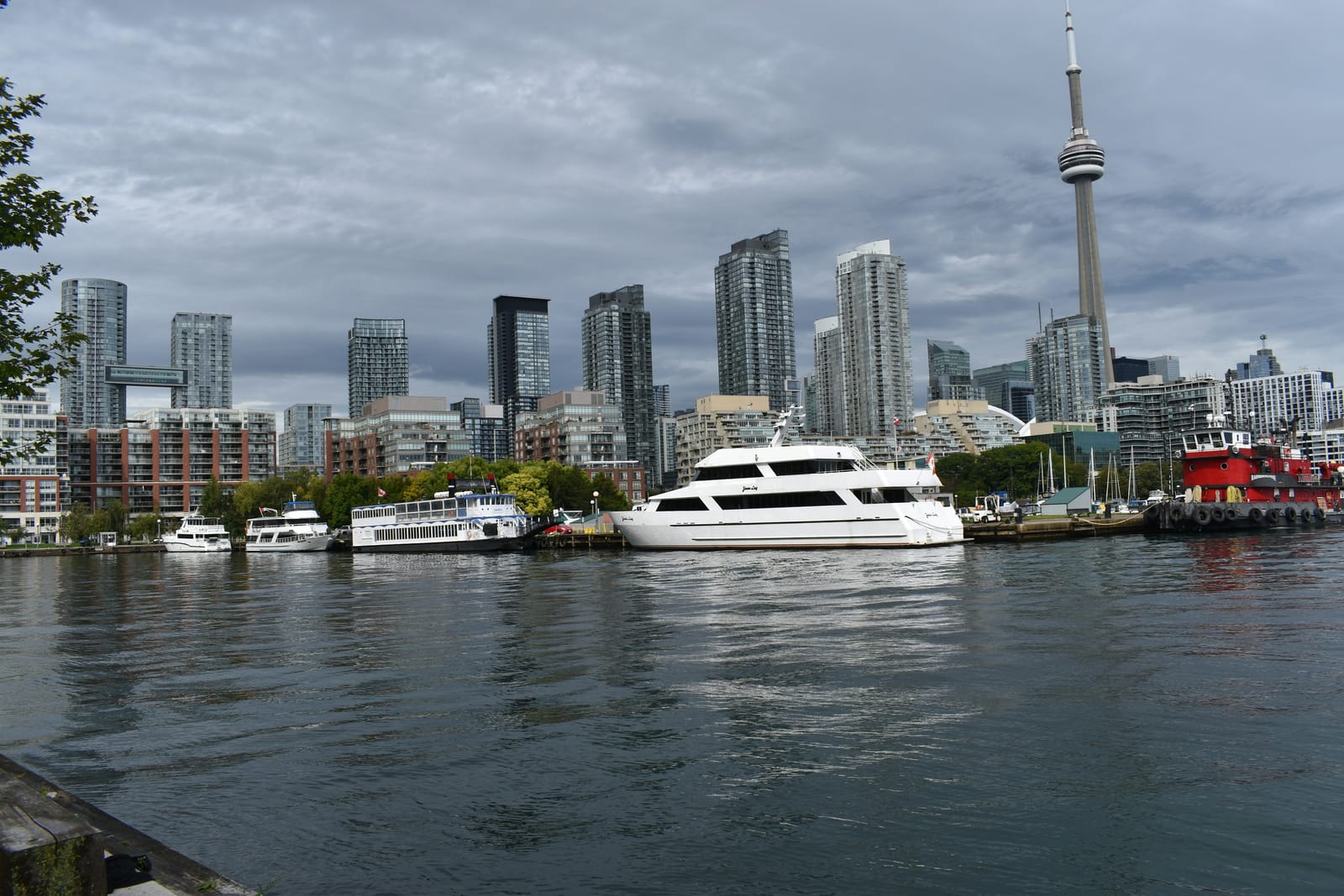 A white boat on Toronto's inner harbour with the downtown skyline behind