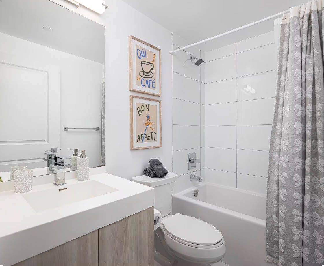 The bathroom of our co-hosted downtown condo: white tile, rolled towels and framed prints