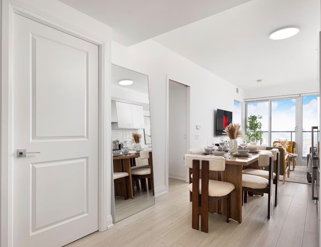The entry hall and dining table of the condo, with the balcony beyond