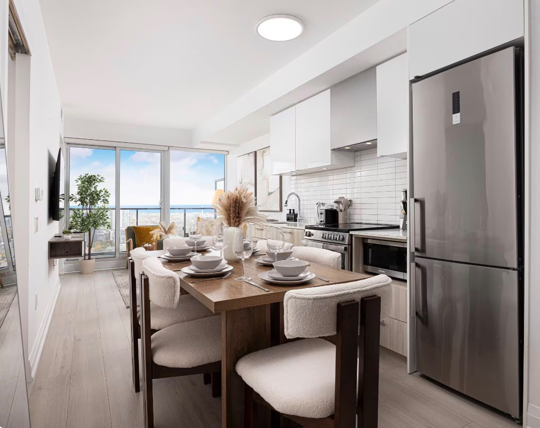 The kitchen and dining table set for four, with the Toronto skyline and lake through the window