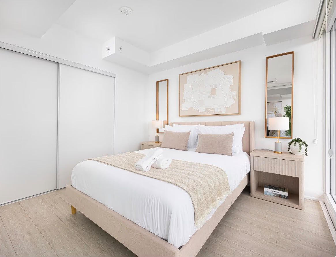 The primary bedroom: queen bed, crisp white linen, two mirrors and bedside lamps
