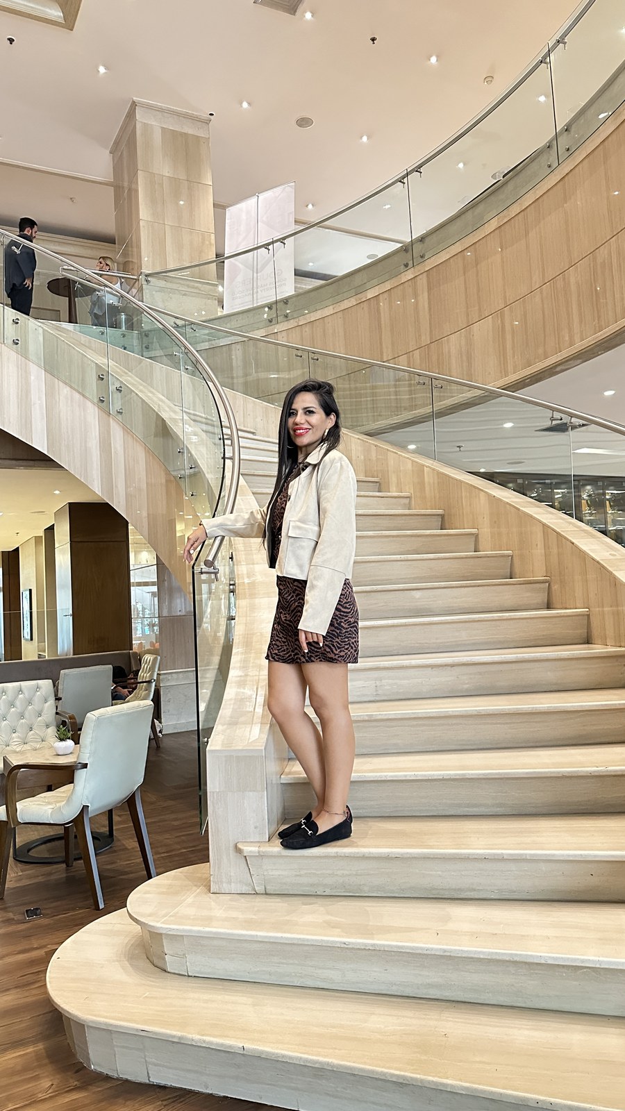 María del Carmen en la escalera de mármol de un lobby de lujo