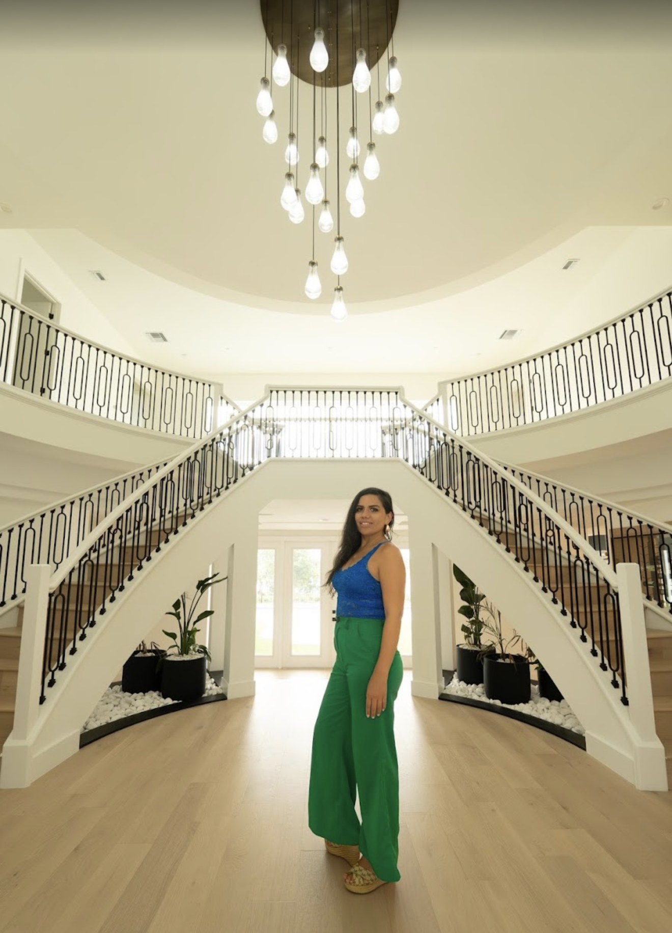 María del Carmen junto a una escalera doble con candelabro en una casa de lujo