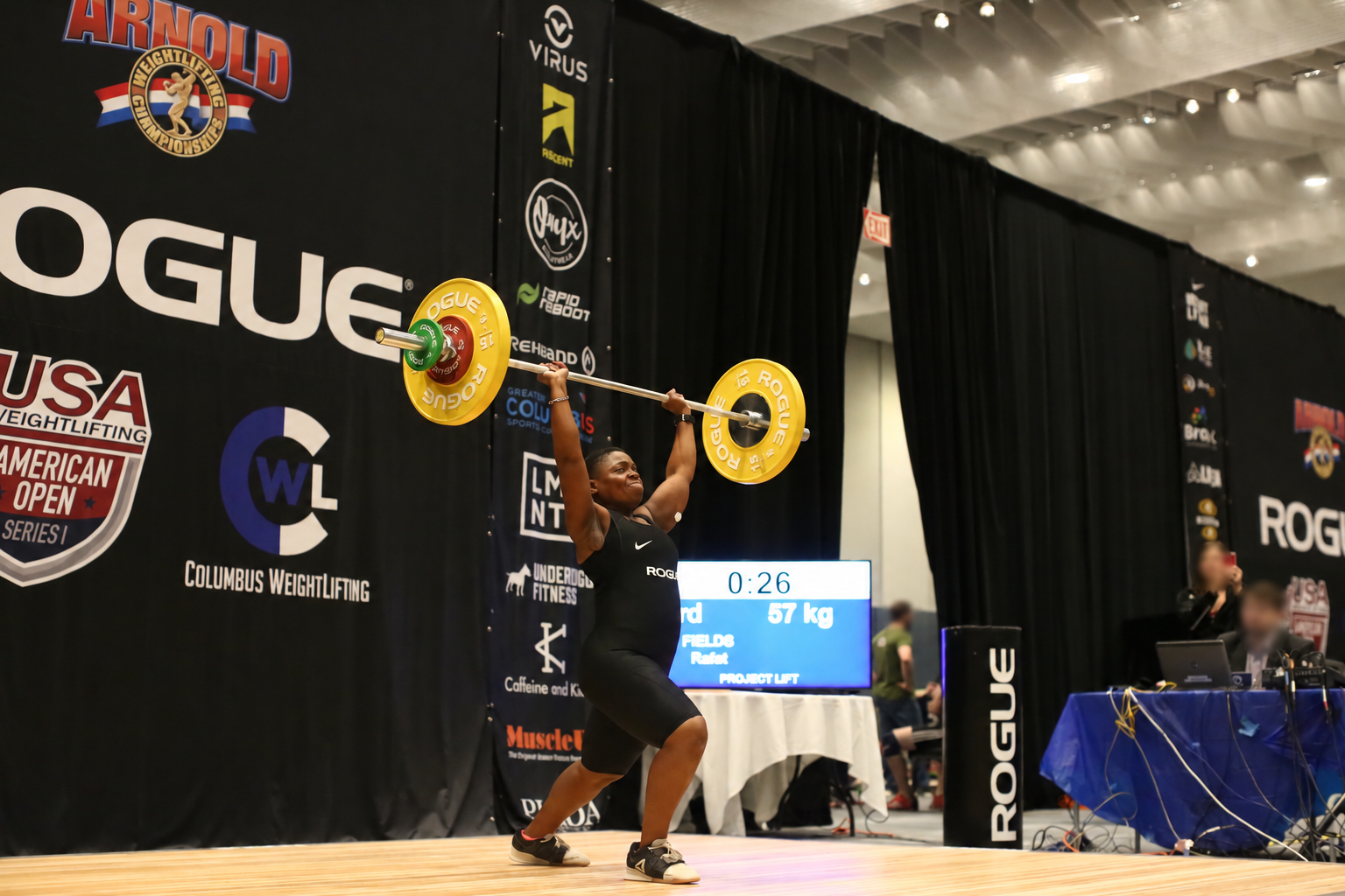 Rafat Fields completing an Olympic lift; background faces blurred