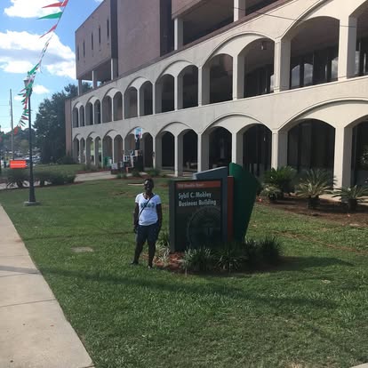 Rafat beside the Sybil C. Mobley Business Building sign at FAMU