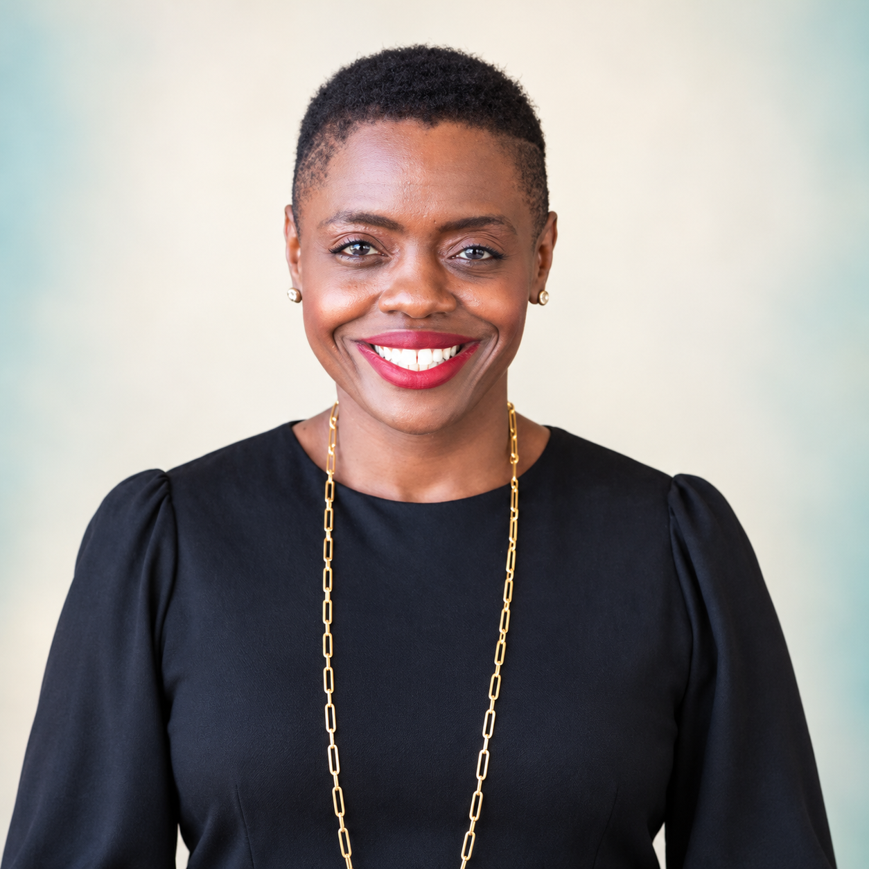 Rafat Fields smiling in a black blouse against a softly lit ivory and teal background.
