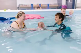 Instructor gently floats a baby on her back in the pool