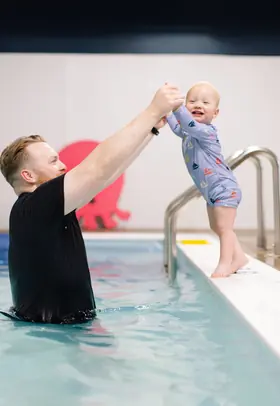 Toddler's arms held up in a high-five victory pose at the pool ladder