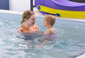 Teen instructor sharing a laughing, face-to-face moment with a toddler boy