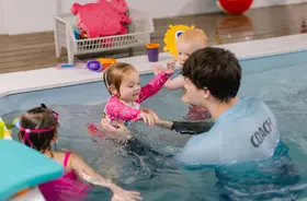Coach playing with two toddlers while a sibling looks on through pink goggles