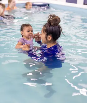Instructor touches fingers with a toddler girl in an eye-to-eye connection moment