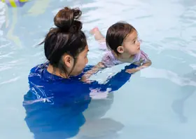 Instructor supports a toddler practicing supported floating