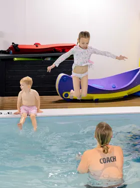 Girl leaping off a foam slide into the pool