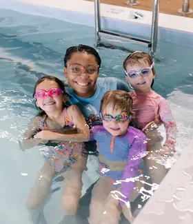 Group portrait of coach with three young swimmers