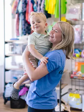 Staff member laughing with a toddler in the lobby retail area