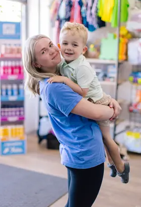 Staff cradling a smiling toddler in the retail corner